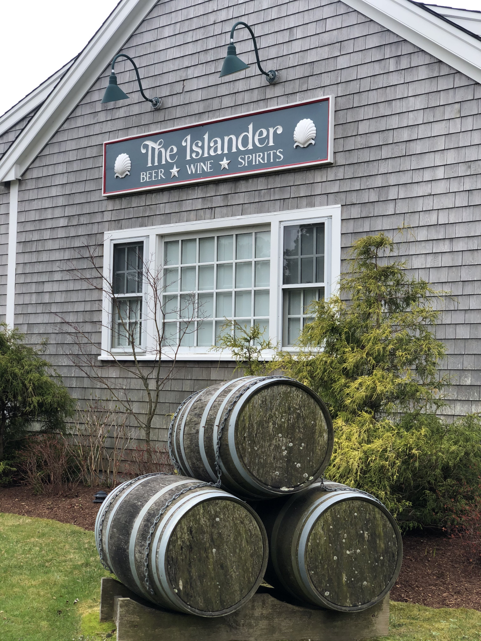 The Islander Nantucket side view of building with three stacked casks in front